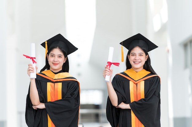 Graduados universitarios femeninos con sombreros negros, borlas amarillas, sonrientes y felices el día de la graduación