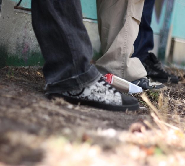 Graffiti hip hop y zapatos de amigos en la pared para el arte callejero de la moda y la relajación urbana creativa y el estilo grunge con zapatillas de deporte de un grupo de adolescentes en el parque para la moda y la lata de aerosol