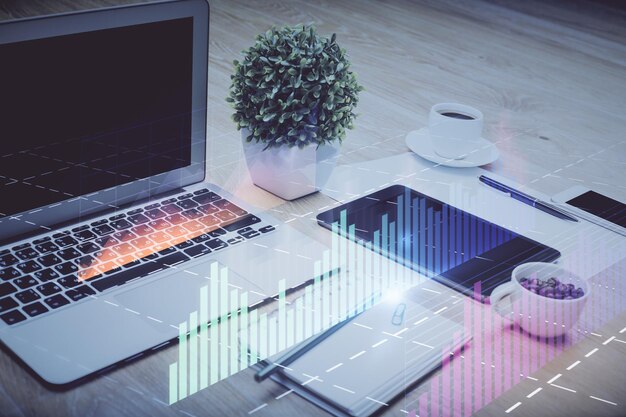 Gráfico bursátil sobre fondo con escritorio y computadora personal Concepto de exposición múltiple de análisis financiero