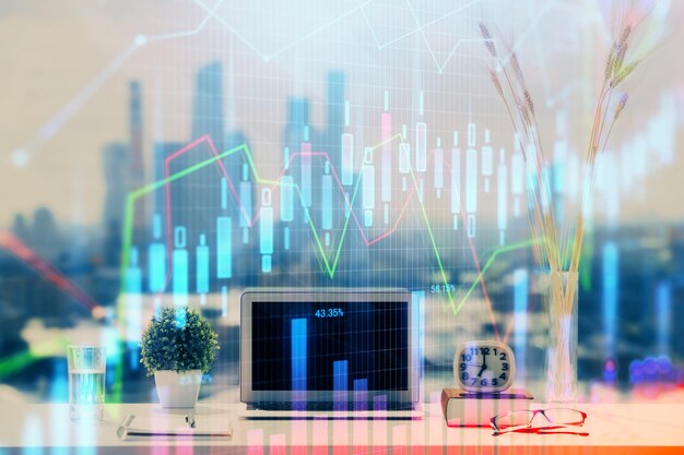 Gráfico bursátil sobre fondo con escritorio y computadora personal Concepto de exposición múltiple de análisis financiero