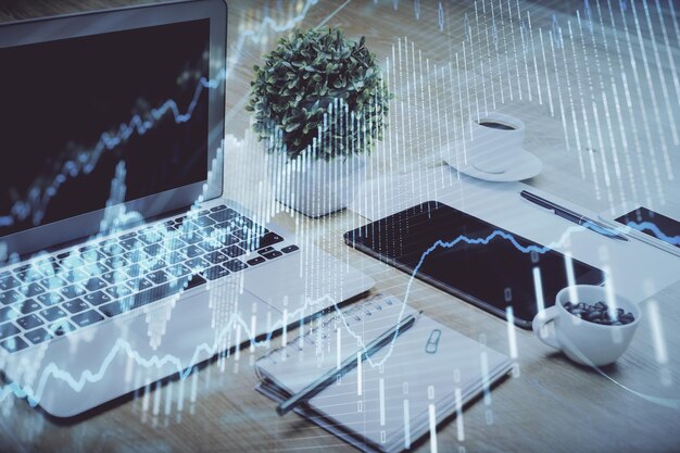 Gráfico bursátil sobre fondo con escritorio y computadora personal Concepto de exposición múltiple de análisis financiero