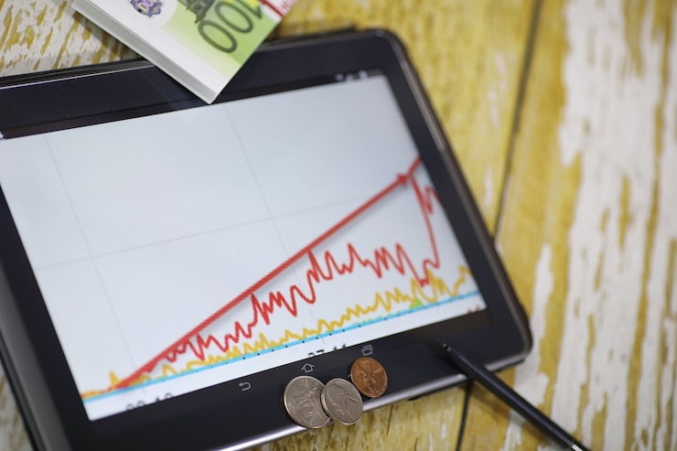 Foto el gráfico de crecimiento de los ingresos. tableta electrónica con gráfico de tasas de crecimiento de ganancias. la moneda en el gráfico del teléfono inteligente.