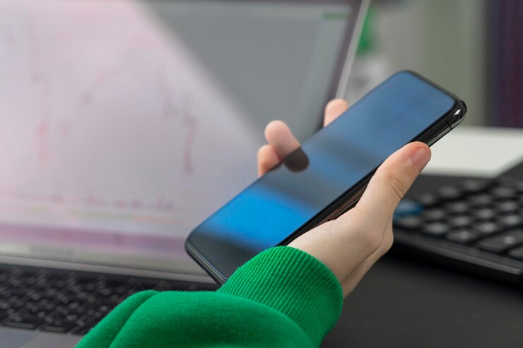 Foto un gráfico descendente en un monitor portátil y un teléfono en manos de una persona que está lista para vender acciones