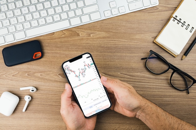 Gráfico do mercado financeiro de ações na tela do smartphone em fundo de madeira. bolsa de valores.