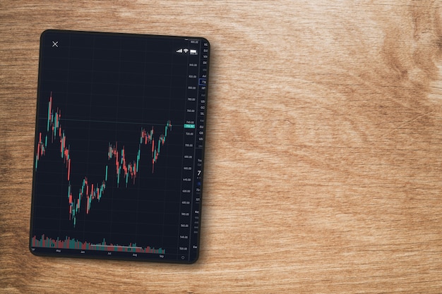 Gráfico do mercado financeiro de ações na tela do tablet em fundo de madeira. Vista do topo. Bolsa de Valores.