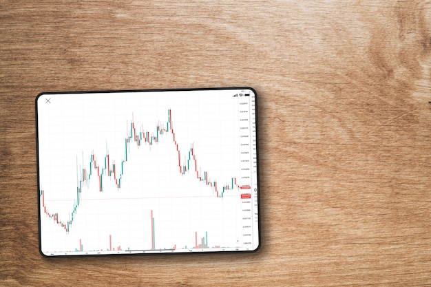 Gráfico do mercado financeiro de ações na tela do tablet em fundo de madeira. Vista do topo. Bolsa de Valores.
