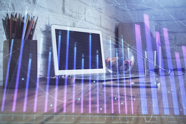 Foto gráfico financiero dibujo colorido y tabla con computadora en el fondo doble exposición concepto de mercados internacionales