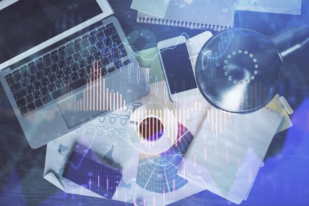 Gráfico del mercado financiero y computadora con vista superior en el fondo del escritorio Concepto de inversión de exposición múltiple