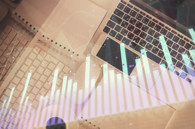 Gráfico del mercado financiero y computadora con vista superior en el fondo del escritorio Concepto de inversión de exposición múltiple