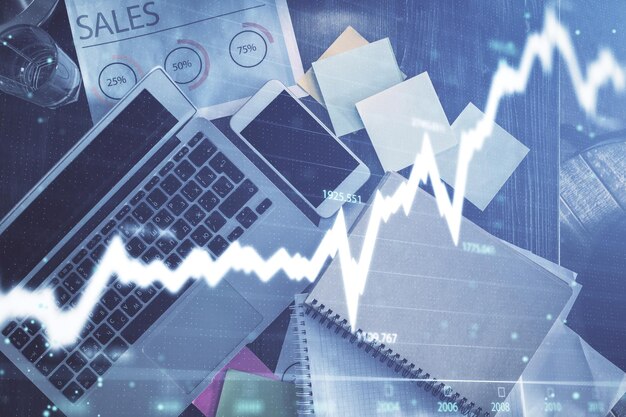 Gráfico del mercado financiero y vista superior de la computadora en el fondo del escritorio Concepto de inversión de exposición múltiple