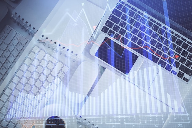 Gráfico del mercado financiero y vista superior de la computadora en el fondo del escritorio Concepto de inversión de exposición múltiple