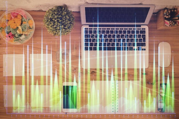 Gráfico del mercado de valores y computadora de vista superior en el fondo de la mesa Concepto de exposición múltiple de educación financiera