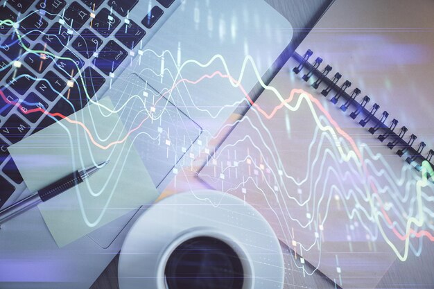 Gráfico del mercado de valores y computadora con vista superior en el fondo de la mesa Doble exposición Concepto de educación financiera