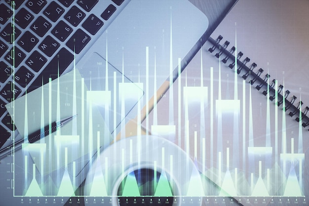 Gráfico del mercado de valores y computadora con vista superior en el fondo de la mesa Doble exposición Concepto de educación financiera