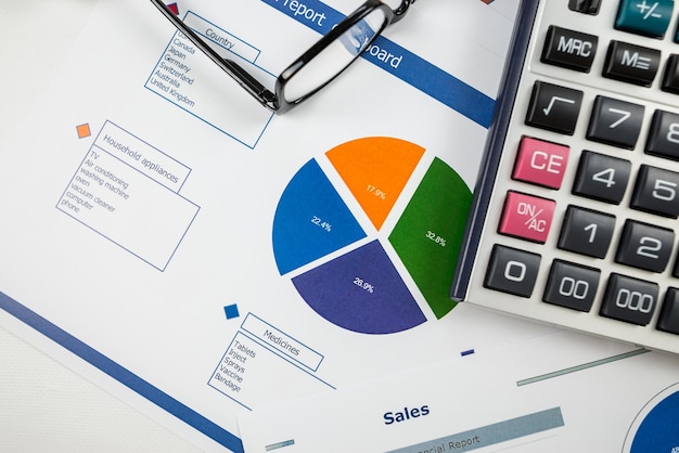 Gráfico de negocios informe de ventas calculadora pluma y anteojos vista superior