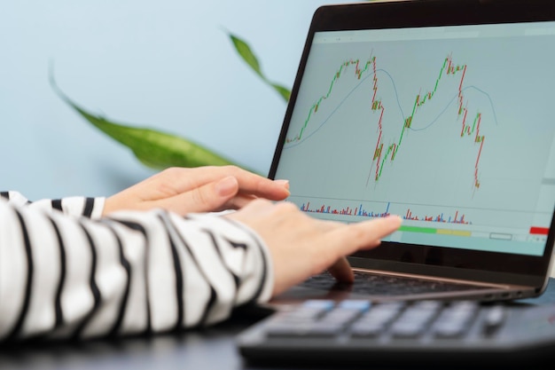 Foto un gráfico que cae en un monitor de computadora portátil y manos listas para hacer un trato de compra de acciones