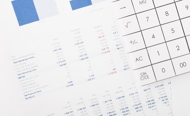 Gráficos financeiros e uma calculadora na mesa do contador. Calculando lucros, impostos e pagando salários de funcionários.