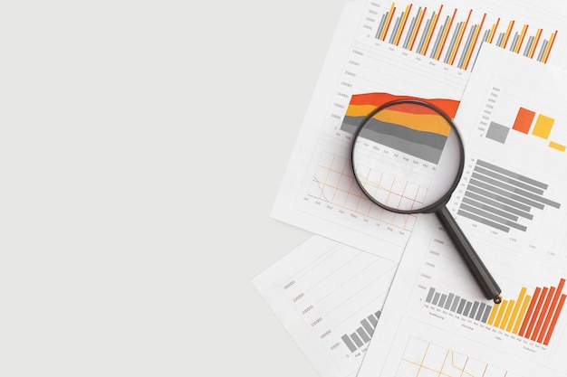 Gráficos de gráficos de negocios y lupa en la mesa Desarrollo financiero Estadísticas de cuentas bancarias