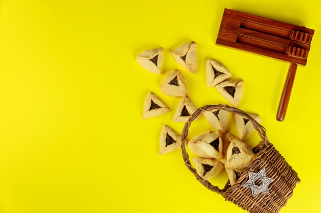 Gragger con galletas sobre fondo amarillo. Fiesta judía de Purim.