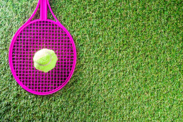 grama verde com raquete de tênis e bola.