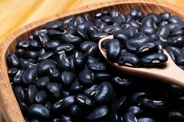 Gramo negro en tazón de madera sobre fondo de mesa de madera