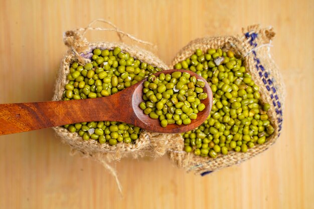 Gramo verde o frijol mungo en bolsa sobre fondo de madera.