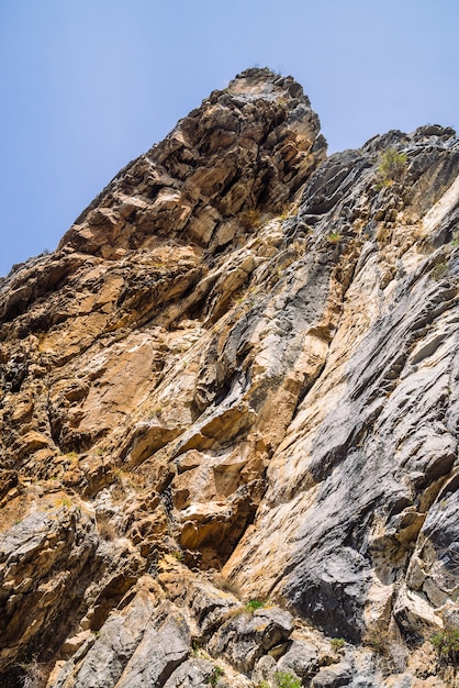 Gran acantilado de la montaña rocosa bajo el cielo azul de cerca