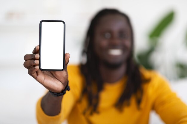 Gran aplicación Hombre negro sonriente que muestra un teléfono inteligente en blanco con pantalla blanca