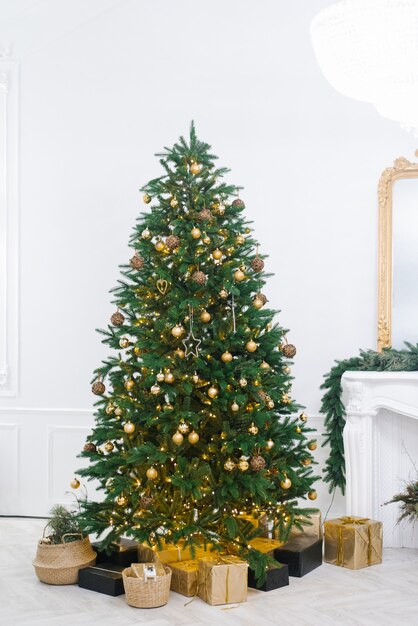 gran árbol de Navidad hermoso decorado con hermosas baratijas brillantes y muchos regalos diferentes en el piso.