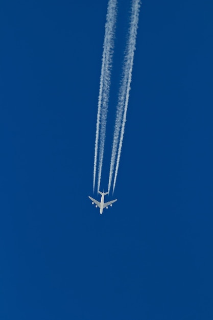 Gran avión de pasajeros vuela dejando un rastro en el cielo despejado