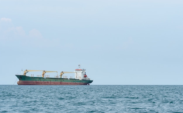 Gran barco con grúa de descarga en el océano y paisaje de cielo azul