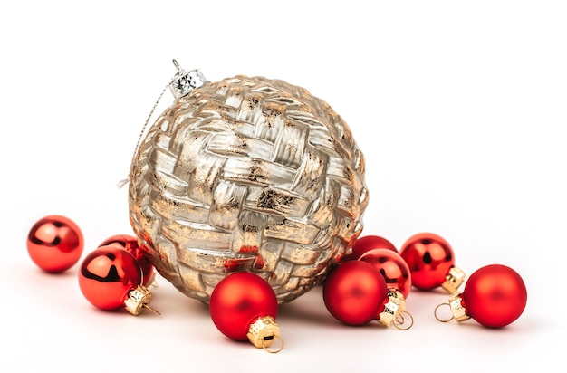 Gran bola de Navidad dorada y pequeñas bolas rojas sobre un fondo blanco aislado.