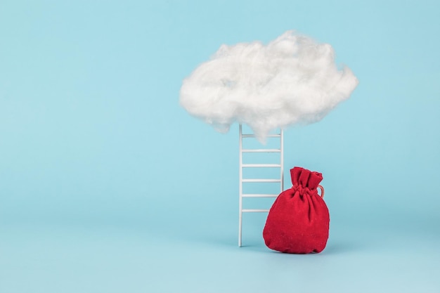 Una gran bolsa roja con regalos cerca de las escaleras que conducen a las nubes.