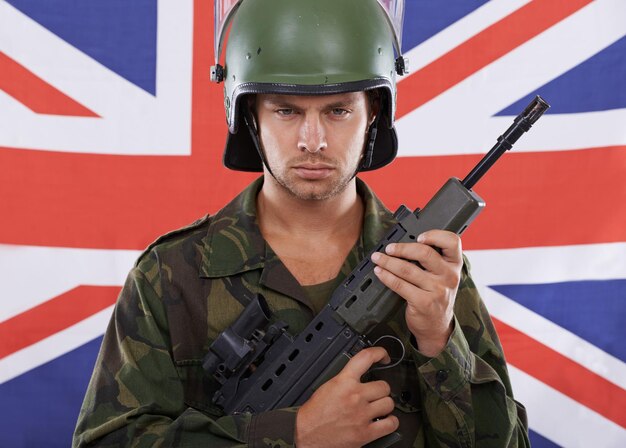 Foto gran bretaña militar y arma con retrato de hombre en estudio para conflicto de guerra y patriótico vigilancia y seguridad del ejército con persona y rifle en bandera británica para campo de batalla de soldados o entrenamiento de veteranos