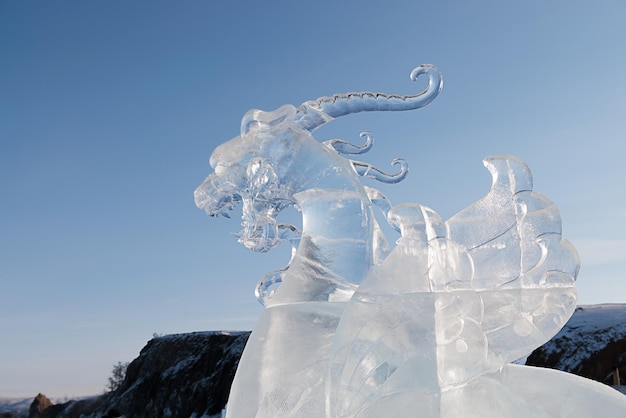 Gran cabeza de dragón hecha de hielo transparente contra el cielo azul Baikal 20 de febrero de 2022