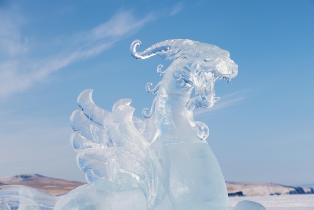 Gran cabeza de dragón hecha de hielo transparente contra el cielo azul