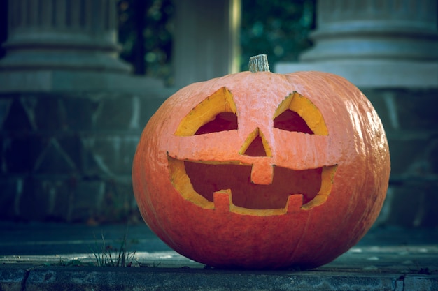 Una gran calabaza naranja con una cara tallada en el crepúsculo.