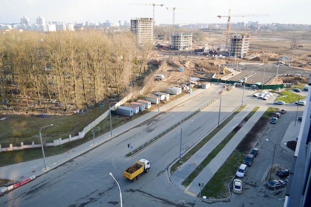 Un gran camión volquete llega a un sitio de construcción y lleva arena a lo largo de una carretera asfaltada