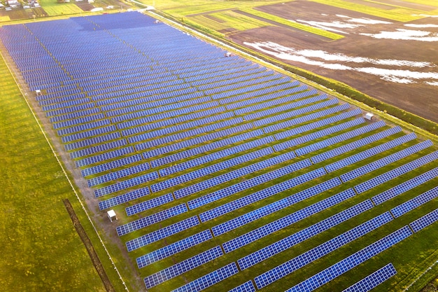 Gran campo de sistema de paneles fotovoltaicos solares que produce energía limpia renovable en la hierba verde.