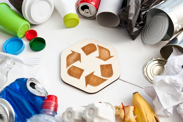 Una gran cantidad de basura diferente en la mesa y el icono de reciclaje entre ellos