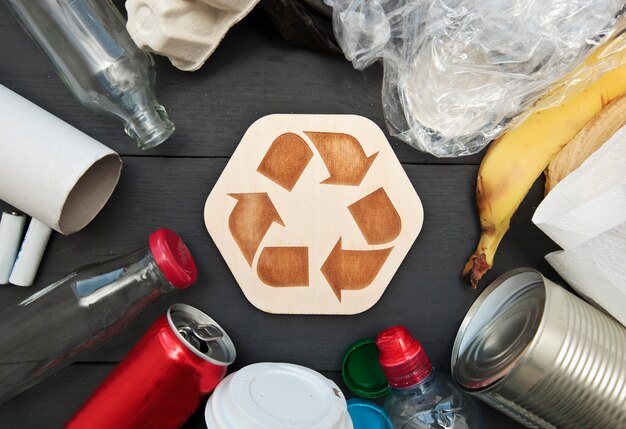 Una gran cantidad de basura diferente en la mesa y el ícono de reciclaje entre ellos