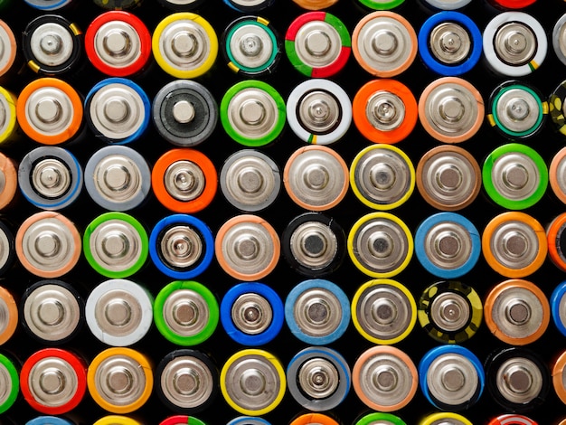 Una gran cantidad de baterías AA viejas de diferentes colores.