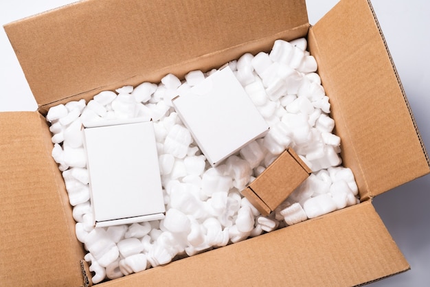 Gran cantidad de cacahuetes de embalaje de envío de relleno blanco sueltos en caja de cartón