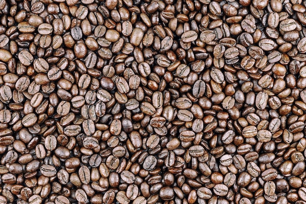 Gran cantidad de granos de café oscuros tostados, ideales para el diseño de cafeterías o menús, vista superior