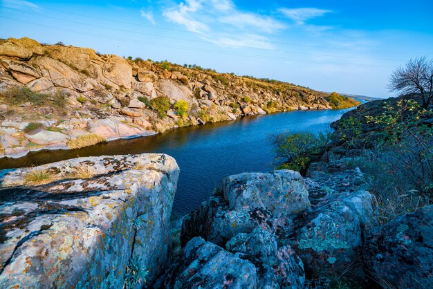 Una gran cantidad de minerales de piedra cubiertos de vegetación verde que se encuentran sobre un pequeño río en la pintoresca Ucrania y su hermosa naturaleza