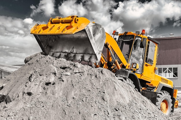 Un gran cargador frontal vierte arena en una pila en un sitio de construcción Transporte de materiales a granel Equipos de construcción Transporte de carga a granel Excavación