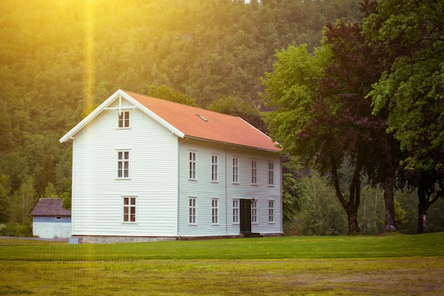 Gran casa de madera noruega tradicional blanca y montañas en la distancia norwayxA