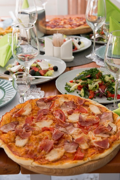 Gran cena con pizza, ensalada y patatas fritas. Cumpleaños, Navidad, Año Nuevo, cena festiva, una mesa, concepto de reunión o celebración.