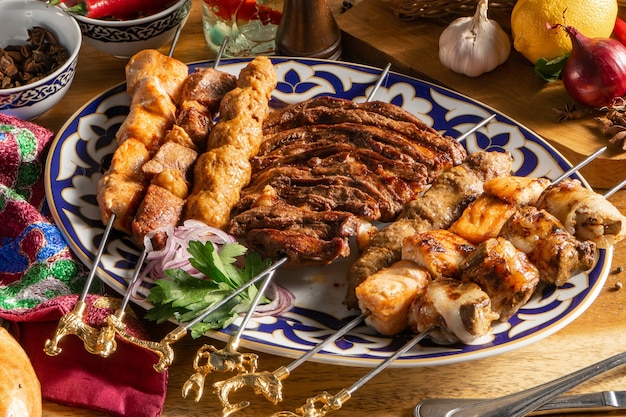 Foto un gran conjunto de diferentes tipos de shish kebab en un plato tradicional uzbeko. shish kebab de cordero, pollo, embutidos caseros, hígado y salmón.