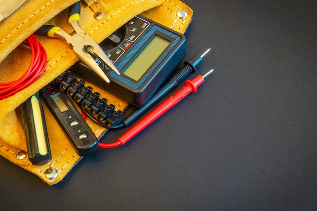 Gran conjunto de herramientas en bolsa de gamuza en espacio negro preparado por el maestro electricista antes de la reparación o construcción